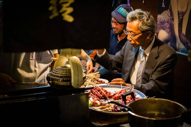 Depois de um dia de trabalho, um empregado de uma multinacional delicia-se com espetadas yakitori numa tasca em Shinjuku.