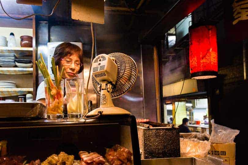 Numa das várias tascas que povoam os becos de Shinjuku, uma senhora prepara uma refeição de espetadas yakitori