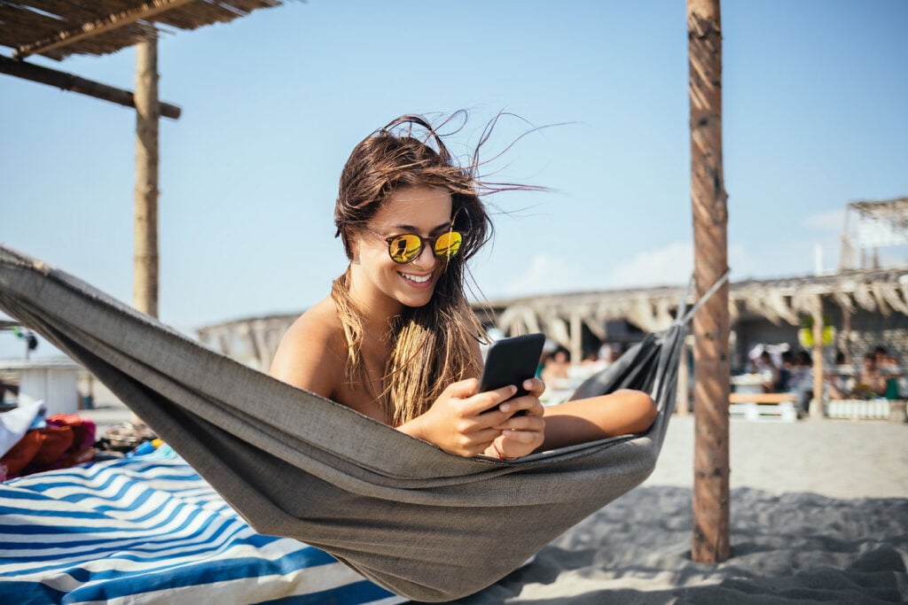 Turista na praia com telefone chip eSIM Brasil da Holafly