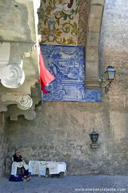 Vendedora de artesanato bordando na entrada principal de Óbidos