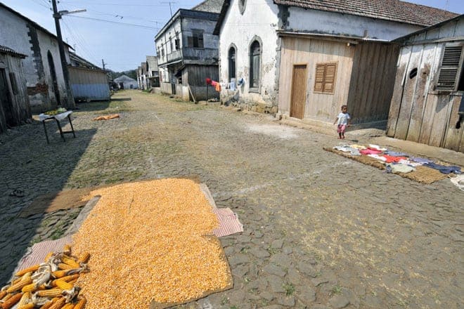 Secando milho e roupa no empedrado de uma ruela